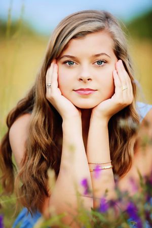 A dreamy outdoor portrait with soft bokeh effect surrounded by purple wildflowers.