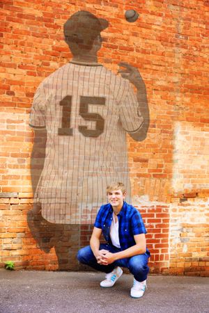 Creative sports portrait with shadow of baseball player number 15 on brick wall.