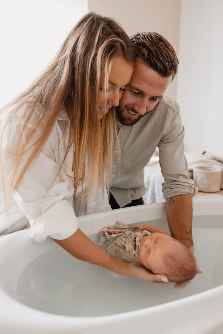 Photographe nouveau-ne Lille, saisissant la magie du bain de Sonia a Avelin pres de Lille : les parents bercent leur tout petit dans le bain