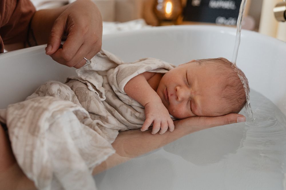 Scene douce d’un bain therapeutique pour bebe, photographie pres de Lille par une photographe naissance.