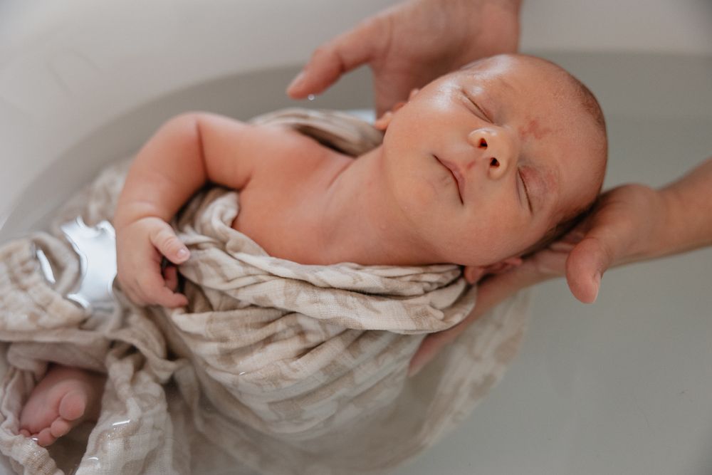 Photographe bebe a Lille, saisissant un moment relaxant de bain therapeutique pour un nouveau-ne.