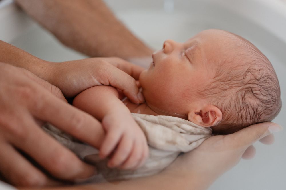 Bebe nouveau-ne dans les mains de ses parents durant un TBB au cabinet Un Mere Veilleux Moment pres de Lille