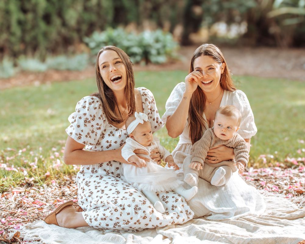 Picnic scene with small baby and others on blanket in sunny garden.