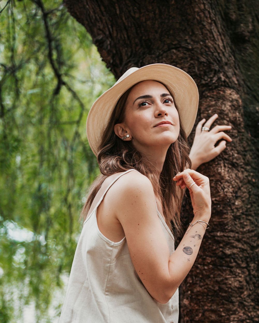 Summer portrait with straw hat against tree trunk and willow branches.