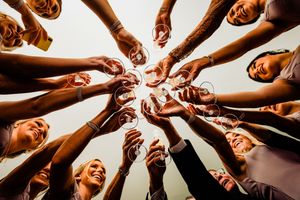 Wedding guests raising champagne glasses in a circle toast, photographed from below.