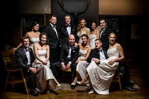 Elegant wedding party group portrait in a dimly lit rustic venue with antler decor.