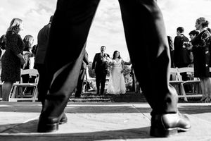 Low angle black and white shot of bride and groom walking down wedding aisle.