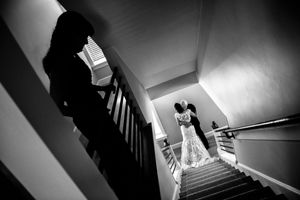 Black and white silhouette of bride and groom kissing on staircase.