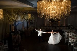 Bride and groom share first dance under stunning crystal chandelier in romantic ballroom.