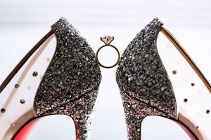 Sparkling glitter bridal heels with diamond engagement ring displayed between the shoes.