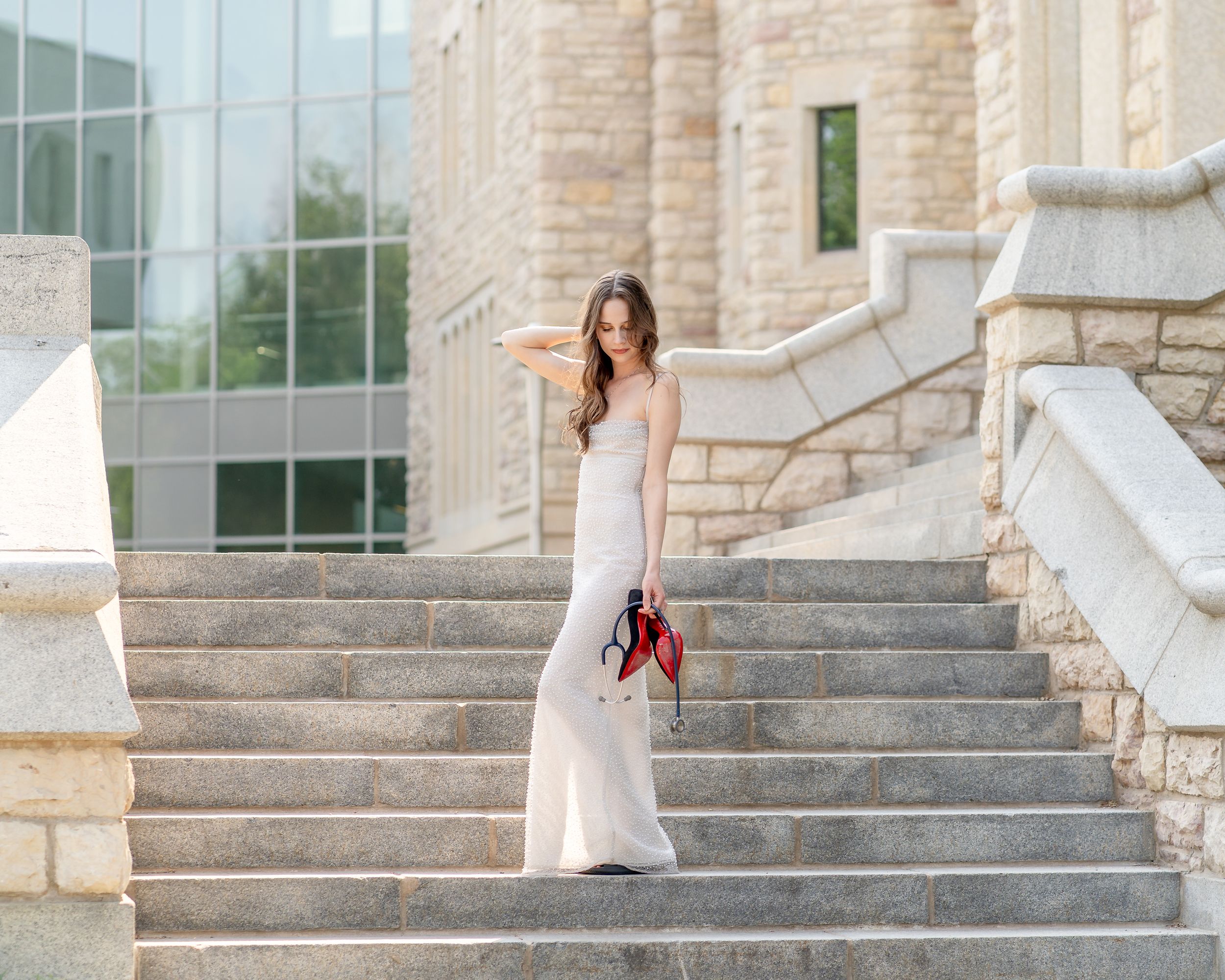 Graduation photos being taken on elegant stone steps of a light limestone building with architectural details.