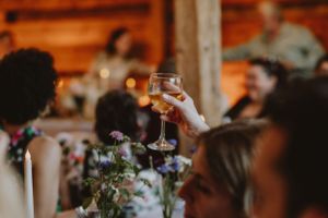 Wedding reception toast with raised champagne glass amid candlelit table decor.