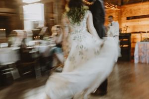 A blurred motion shot of a couple dancing at a rustic wedding reception with a flowing white dress swirling.