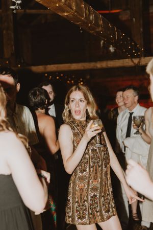 Wedding reception dance party with guests celebrating in rustic barn setting.