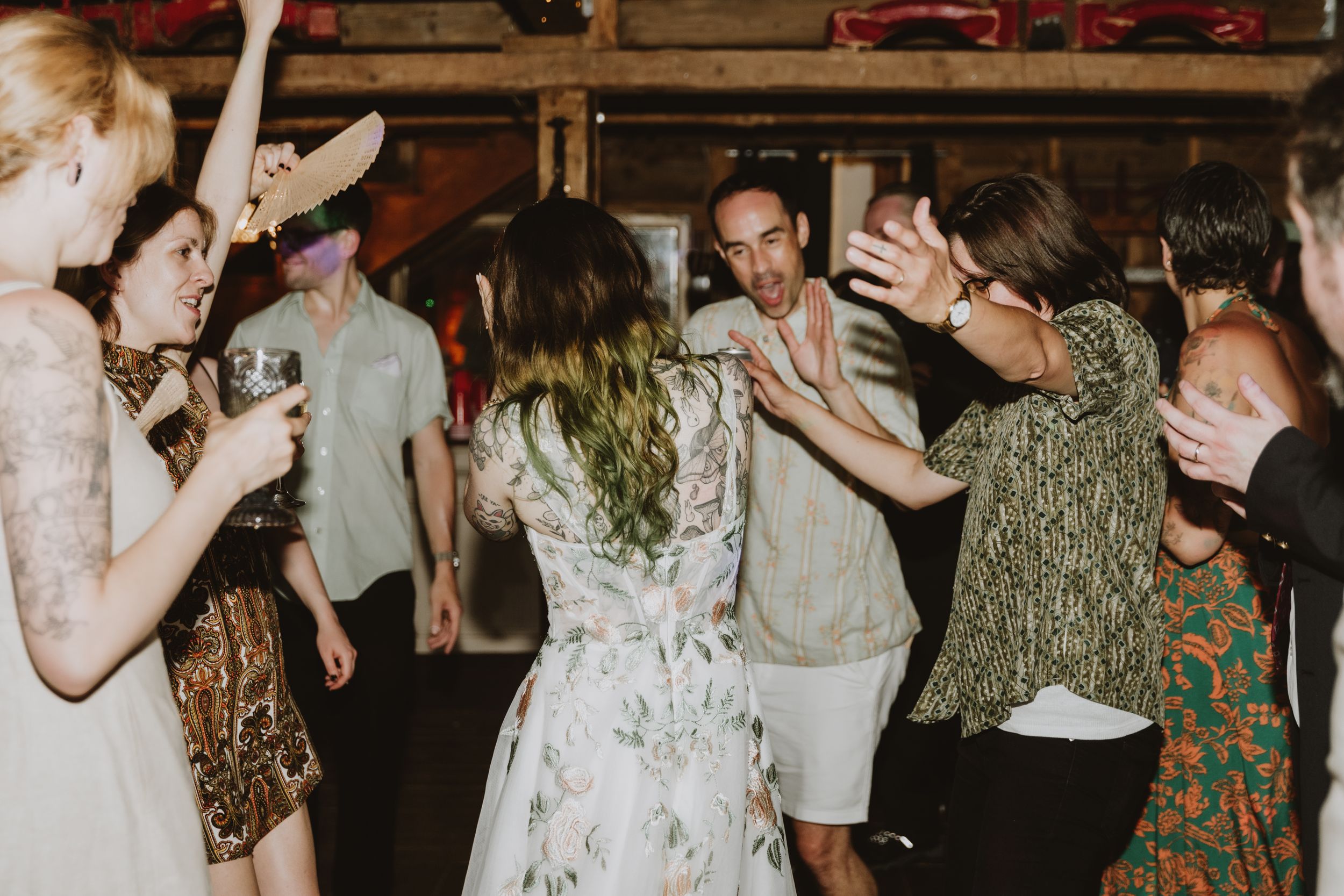 People dancing and having fun at a party in what appears to be a rustic indoor venue with wooden walls.