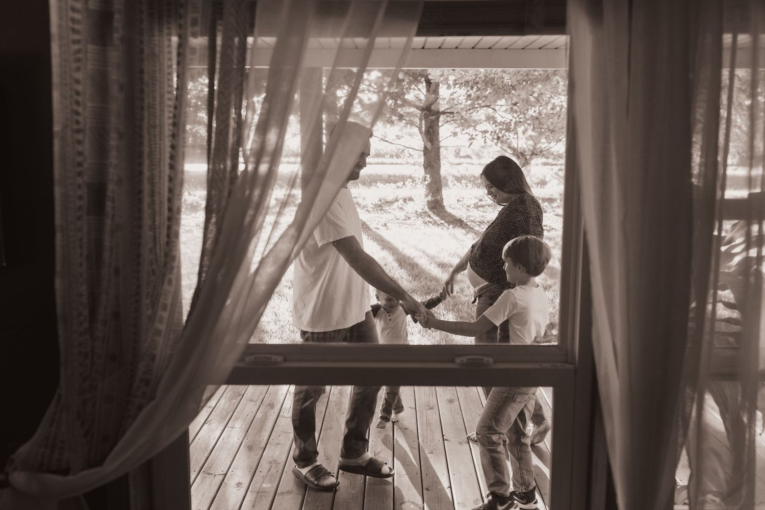 Family embraces on their porch during a lifestyle shoot at their home near Middletown, OH. Photographed by Vicci Photo of Dayton, OH
