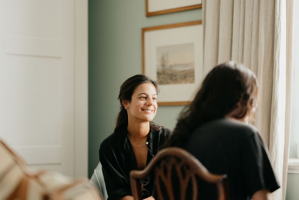 People chatting and smiling in a bright room with gold-framed artwork on mint green walls.