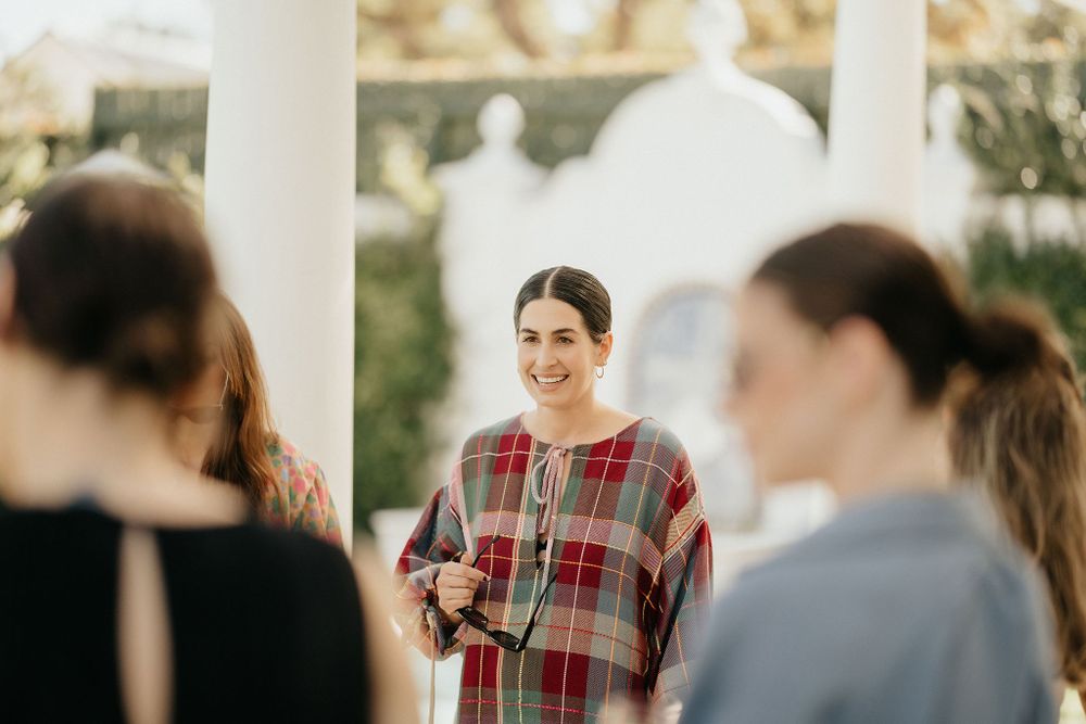 A casual outdoor gathering showing people conversing in a covered patio space with natural lighting.
