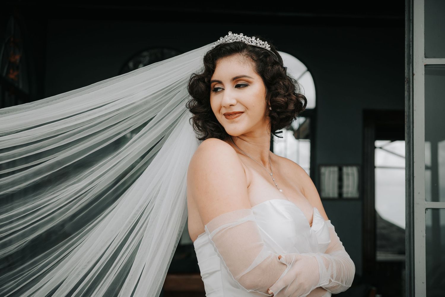 Elegant bridal portrait featuring a flowing veil and classic vintage-inspired styling.