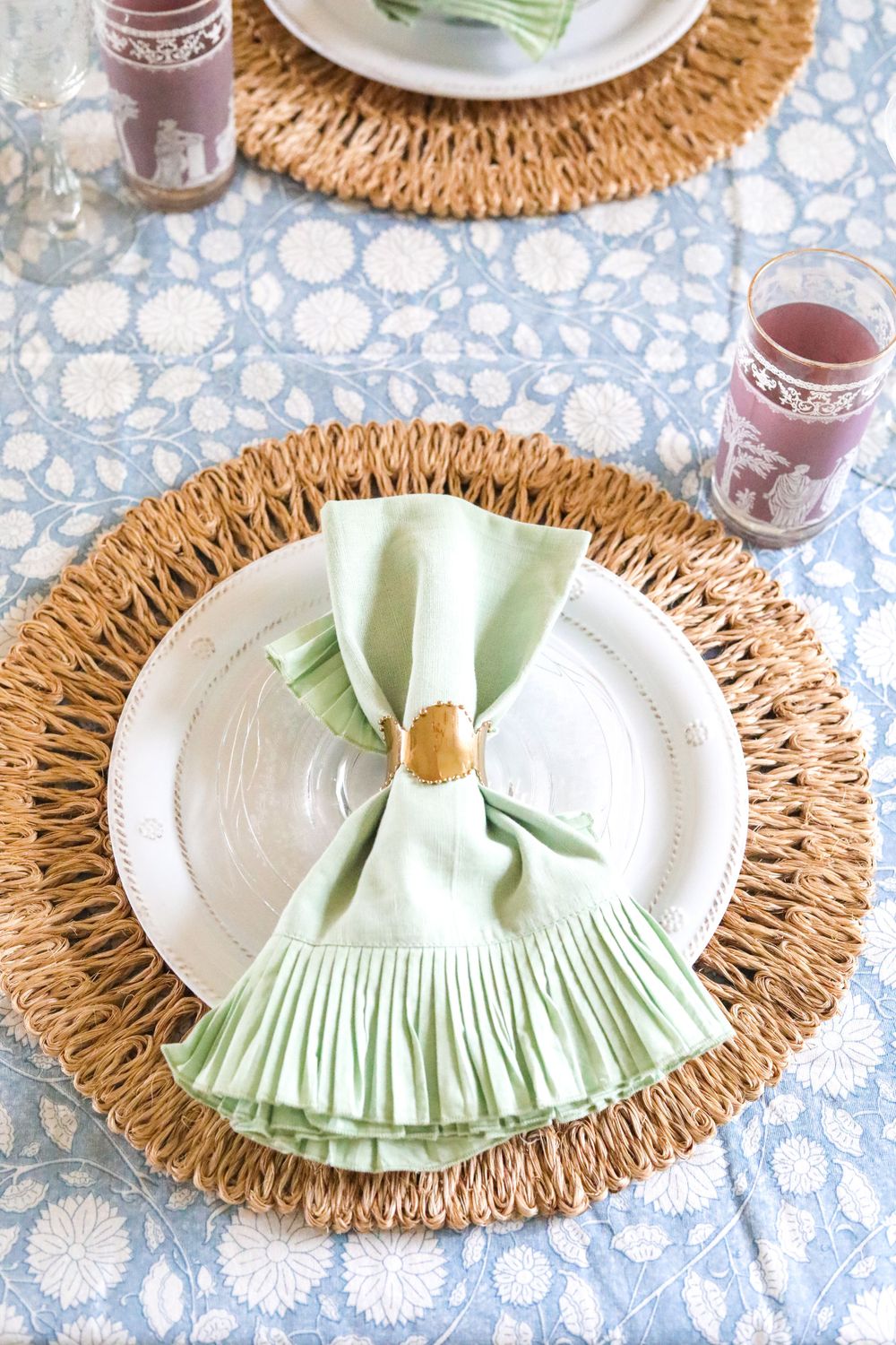 Place settings with mint green napkins arranged on woven rattan charger plates.