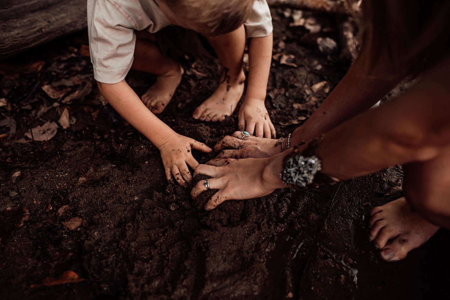 Small hands press into dark soil during an outdoor nature activity.