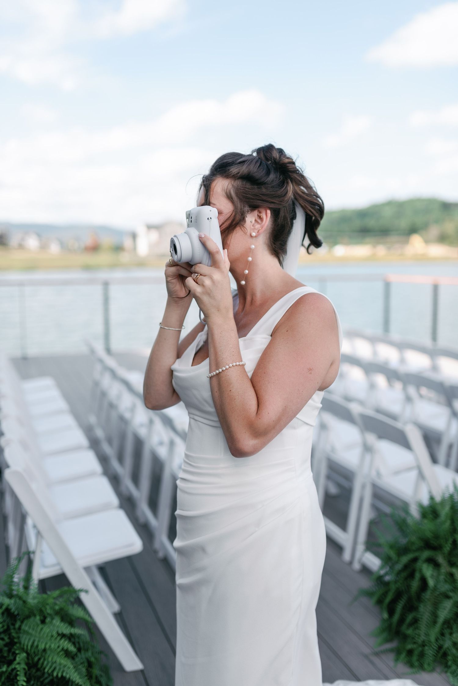 An emotional moment captured as someone dabs tears in white dress by ceremony chairs.