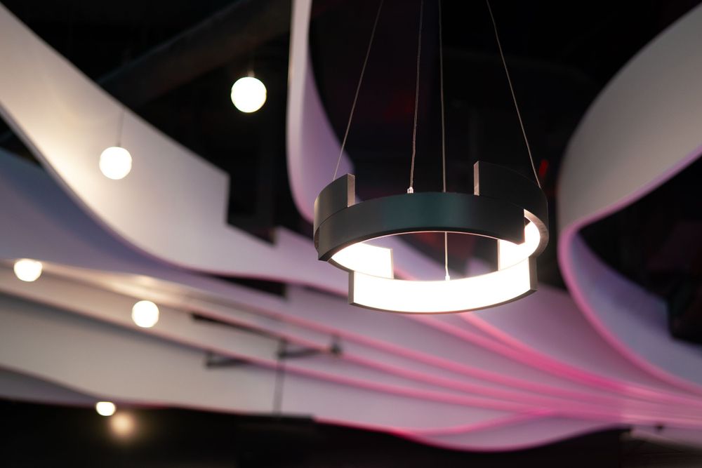 Modern interior space with wavy white ceiling design and pendant lighting.