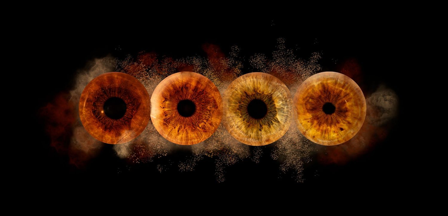 Row of four glowing amber iris patterns arranged horizontally with dark smoky effects against black background.