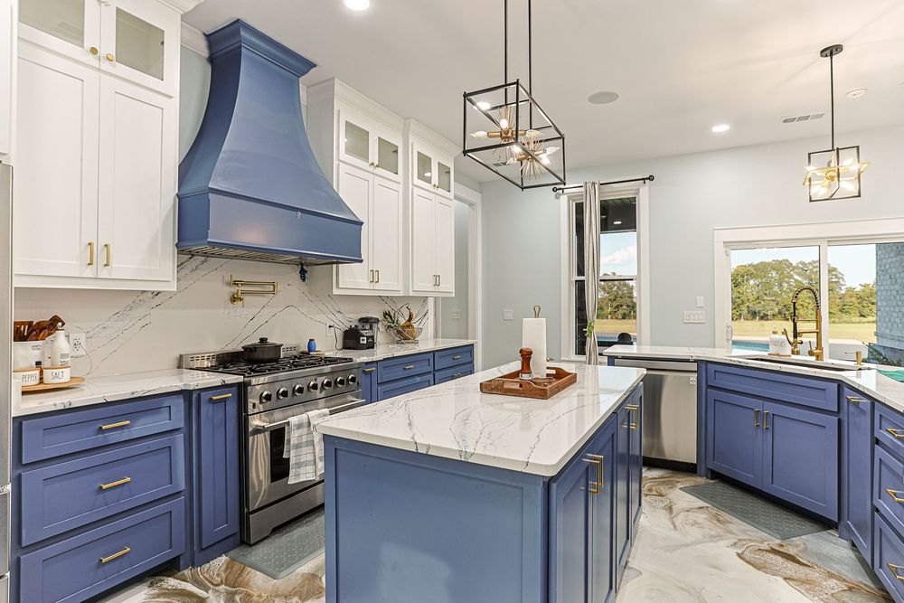 Modern kitchen with navy blue cabinets, white countertops, and gold accents showcases a sleek transitional design style in Taylor, AL.