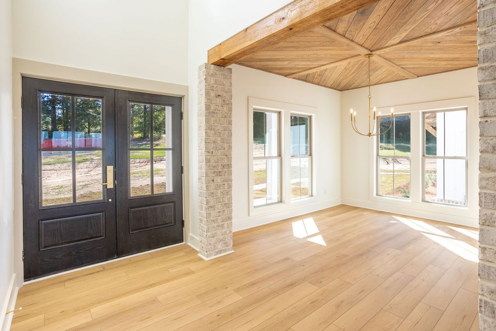 Modern open concept living space with hardwood floors, white walls, and large windows providing natural light in Ozark, AL.