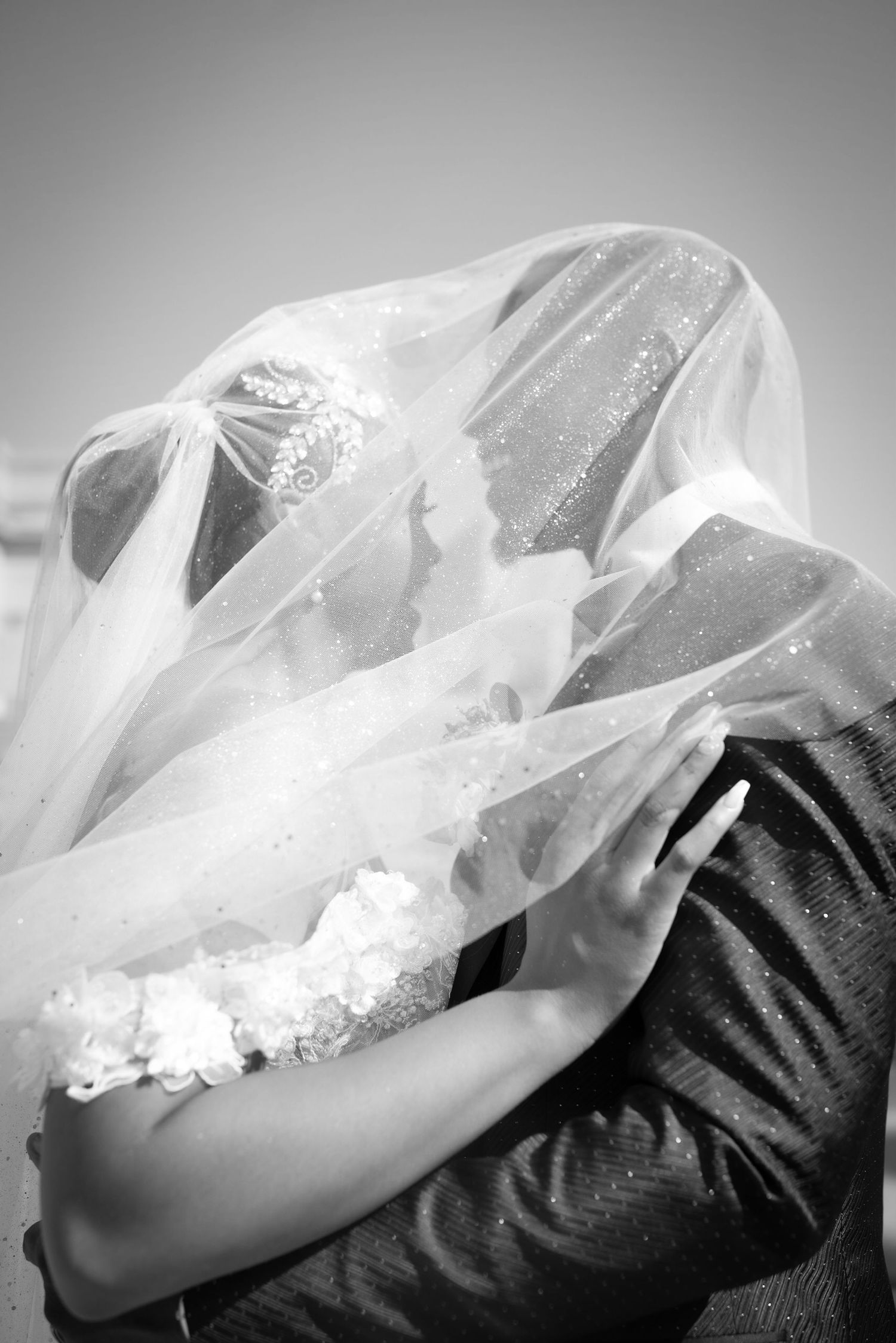 Close-up artistic series of flowing white wedding veil details against dark background.