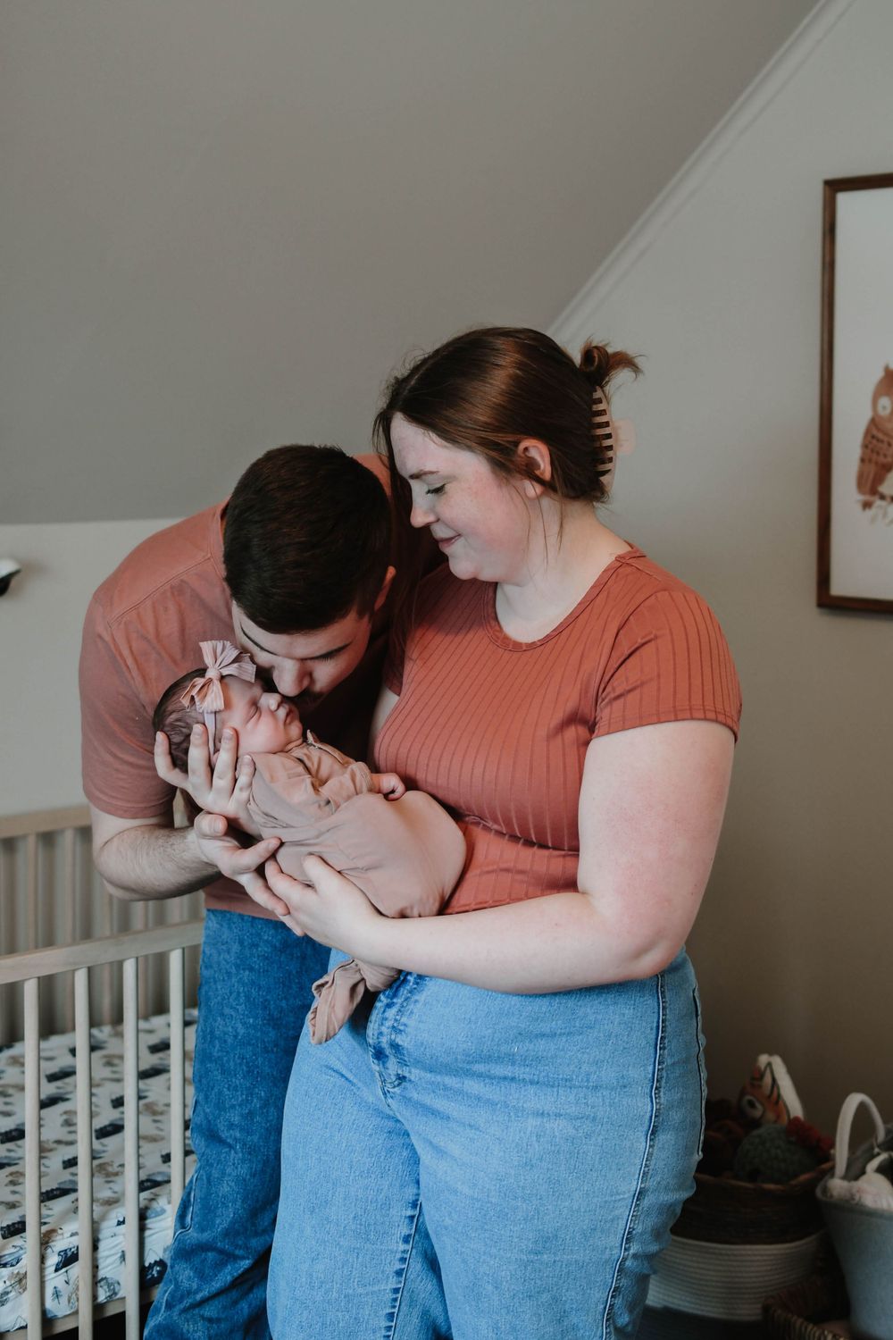 A tender family moment in a nursery as parents lovingly gaze at their newborn baby.