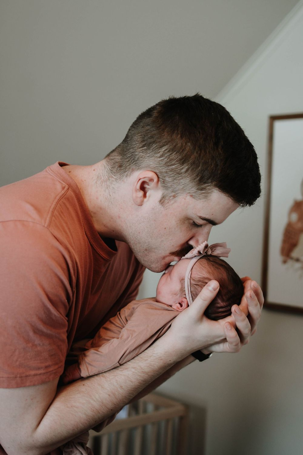A tender moment between a parent and newborn baby in a softly lit nursery room.