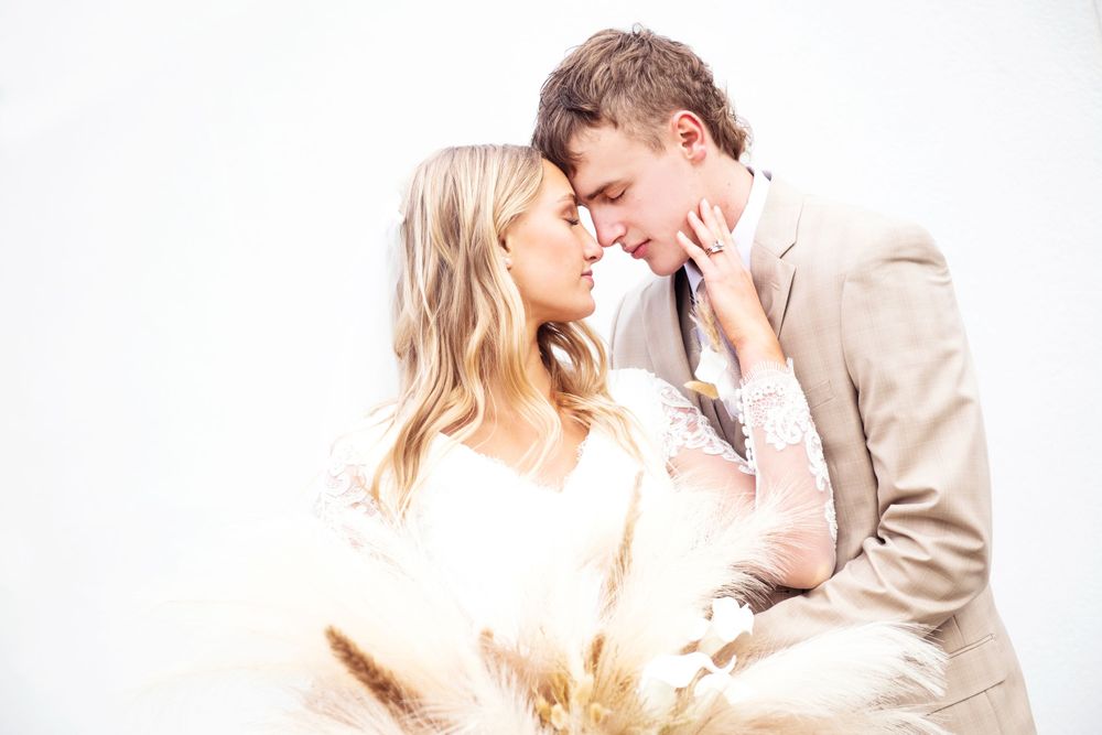 Tender moment between couple in soft white winter wedding photography session.