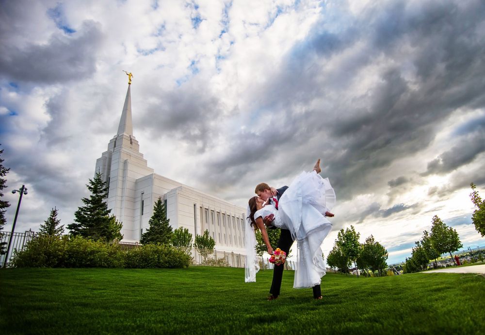A dramatic wedding photo in front of a white temple with stormy clouds overhead.