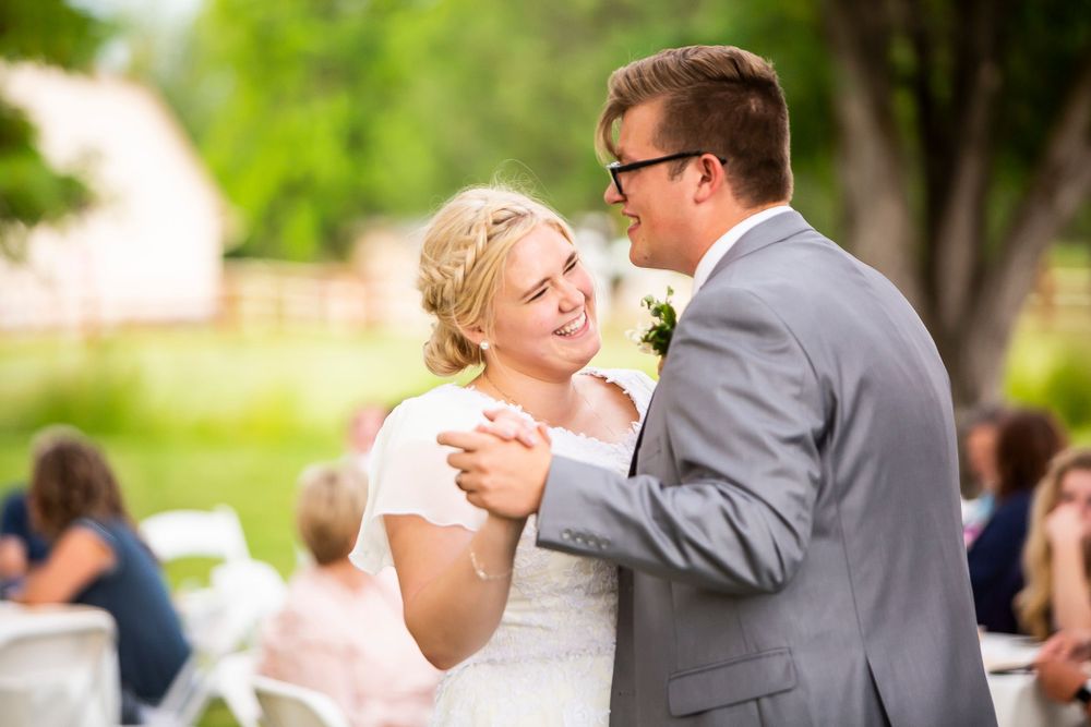 A bride and groom share a joyful dance moment together at an outdoor wedding reception.