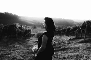 Ritratto artistico in bianco e nero di una mamma incinta in abito nero aderente per esaltare la silhouette.