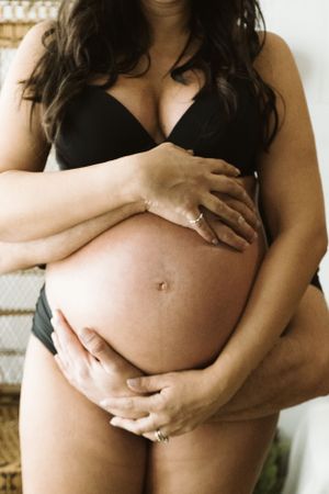 Serie ravvicinata di mani che cullano la pancia incinta in foto artistiche di maternità.