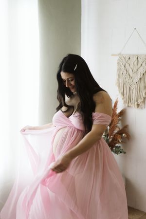 fotografia di una Mamma in dolce attesa in un abito maternità rosa nel mio studio a Cassine.