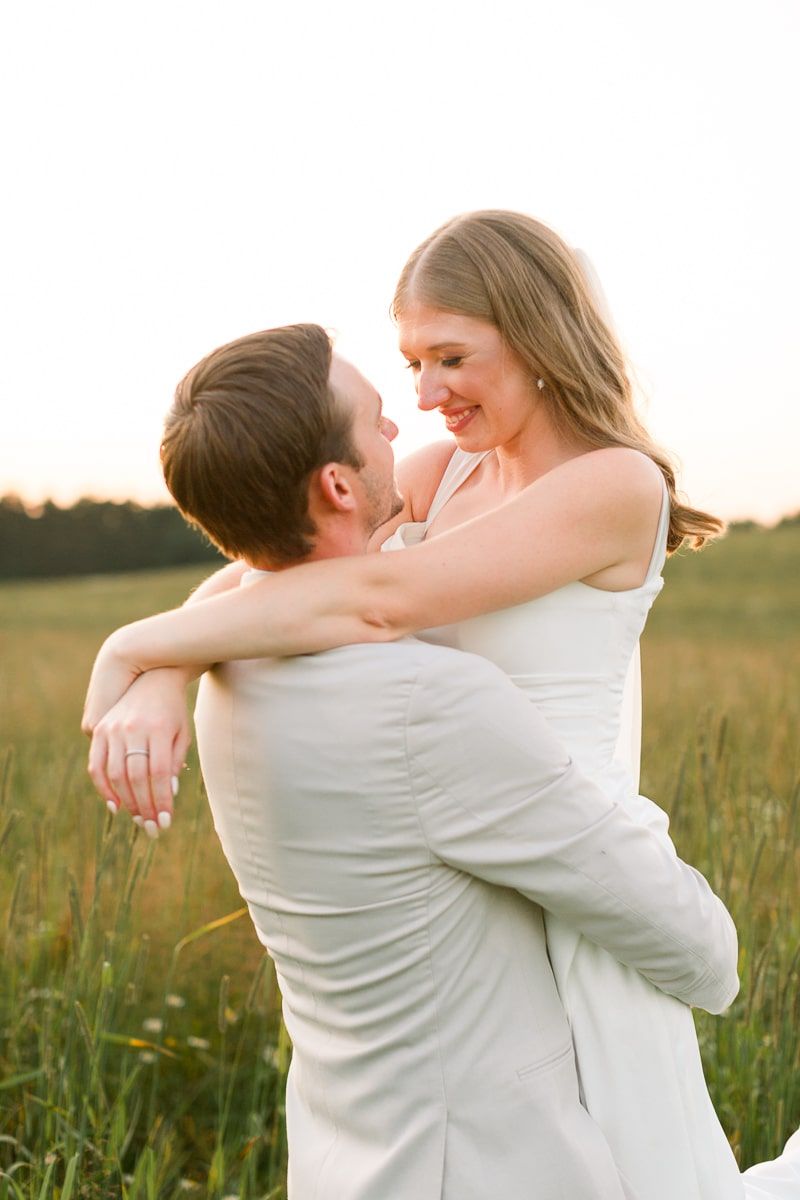 Nate lifts Jenna in the air and they smile together during sunset at Lilydale Event Venue