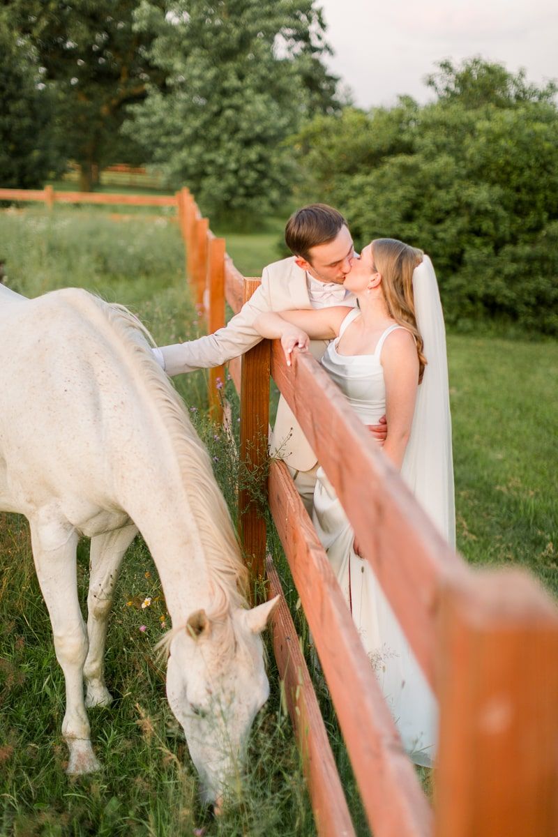 Nate and Jenna pet the horses as they kiss during sunset at Lilydale