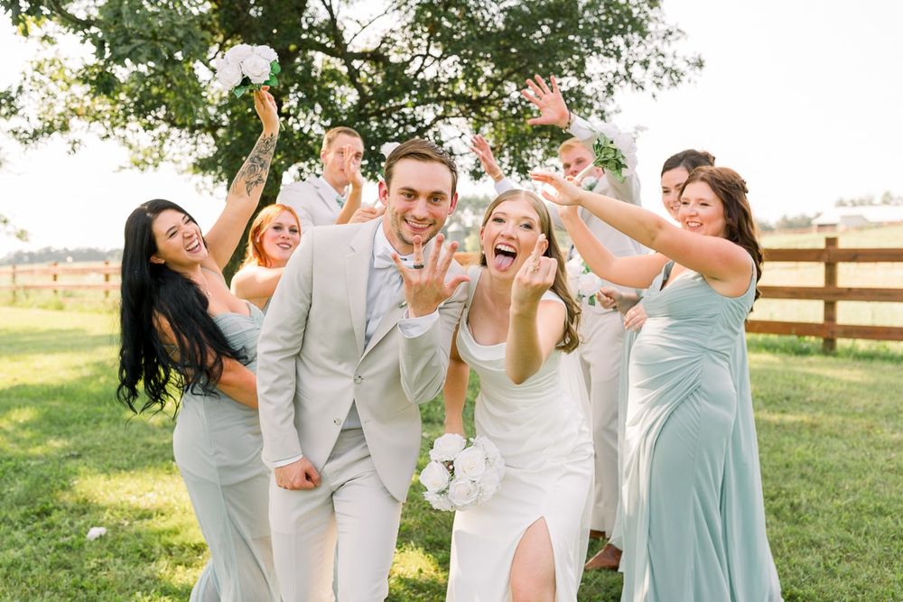Nate and Jenna show off their wedding bands as they pose and smile with their wedding party
