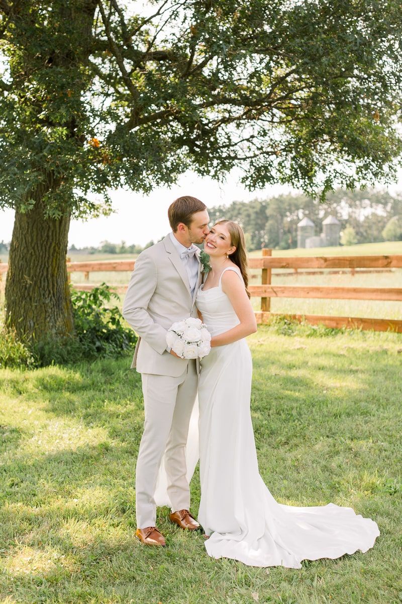 Nate kisses Jenna's cheek as they embrace under a tall oak tree