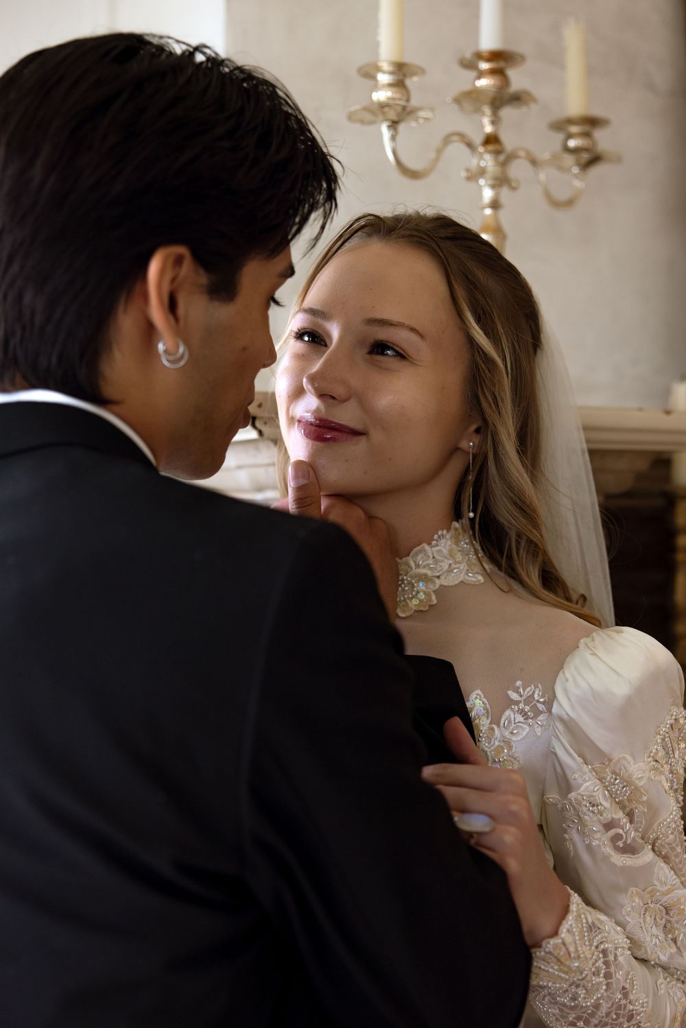 A romantic wedding moment captured with an elegant candelabra in the background, showcasing the bride in delicate lace.