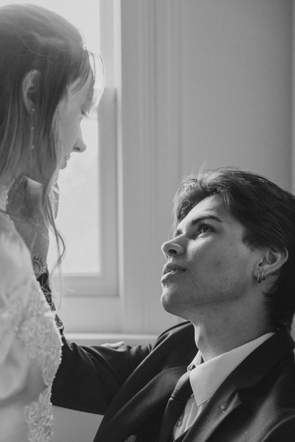 A romantic black and white photograph of a couple sharing an intimate moment by a window.