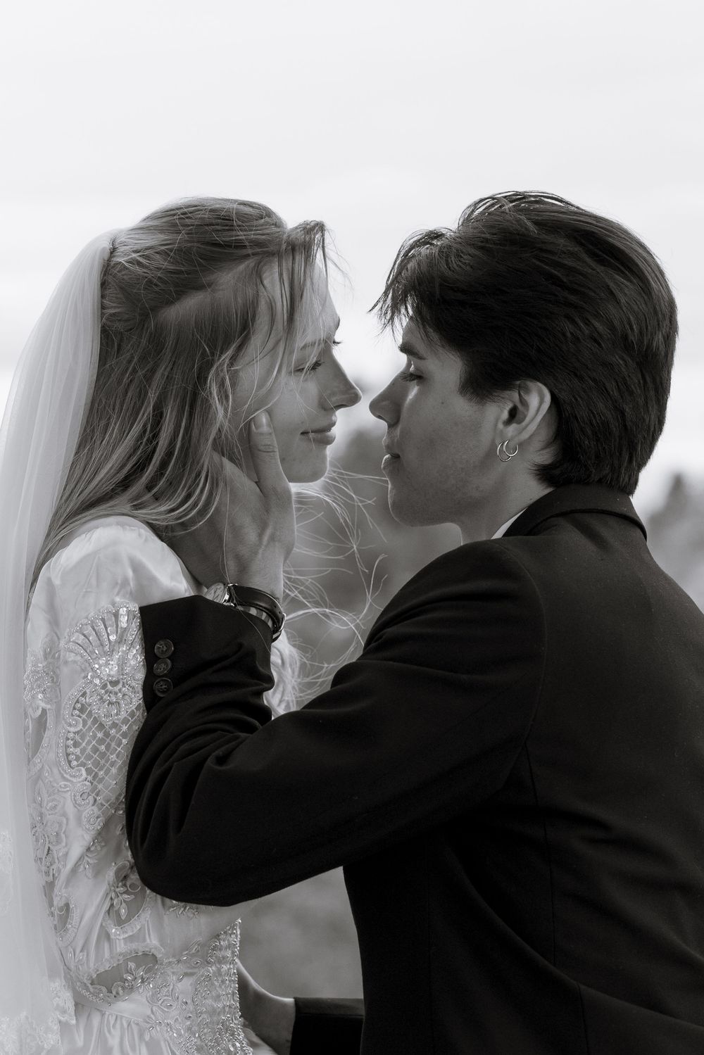 A romantic black and white photograph of a bride and groom sharing an intimate moment during their wedding ceremony.