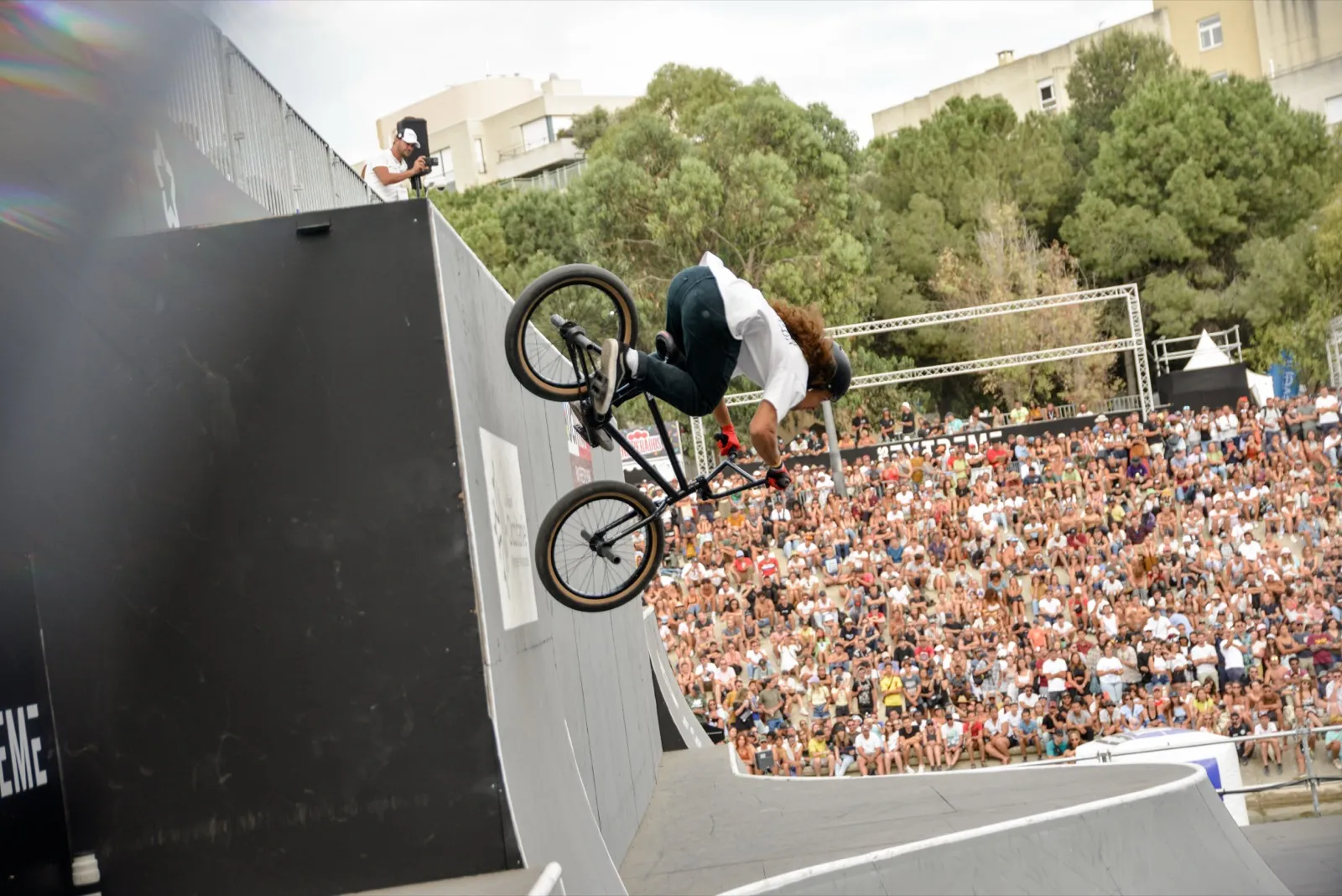 Rider BMX en plein wallride sur une rampe, foule dense en arrière-plan.