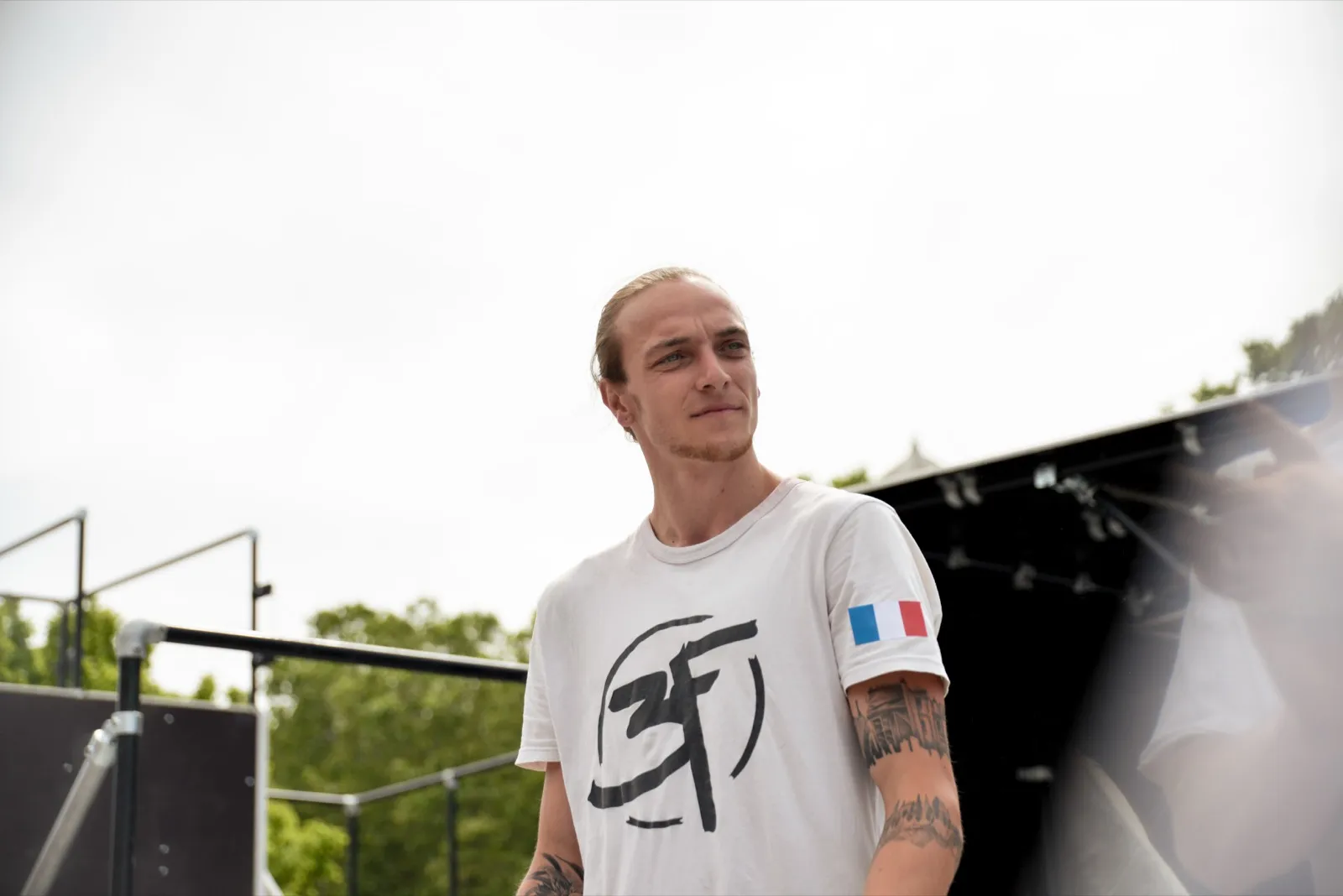 Portrait d’un rider debout, tee-shirt blanc et regard tourné vers l’horizon.