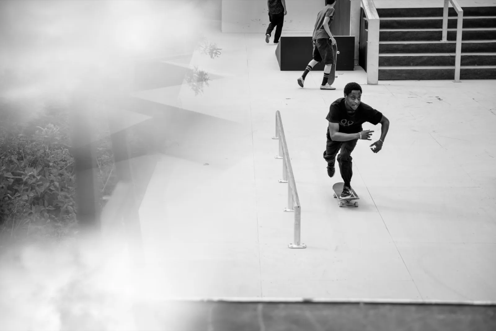 Skateur descendant une rampe dans un environnement urbain, photo en noir et blanc avec flou artistique.