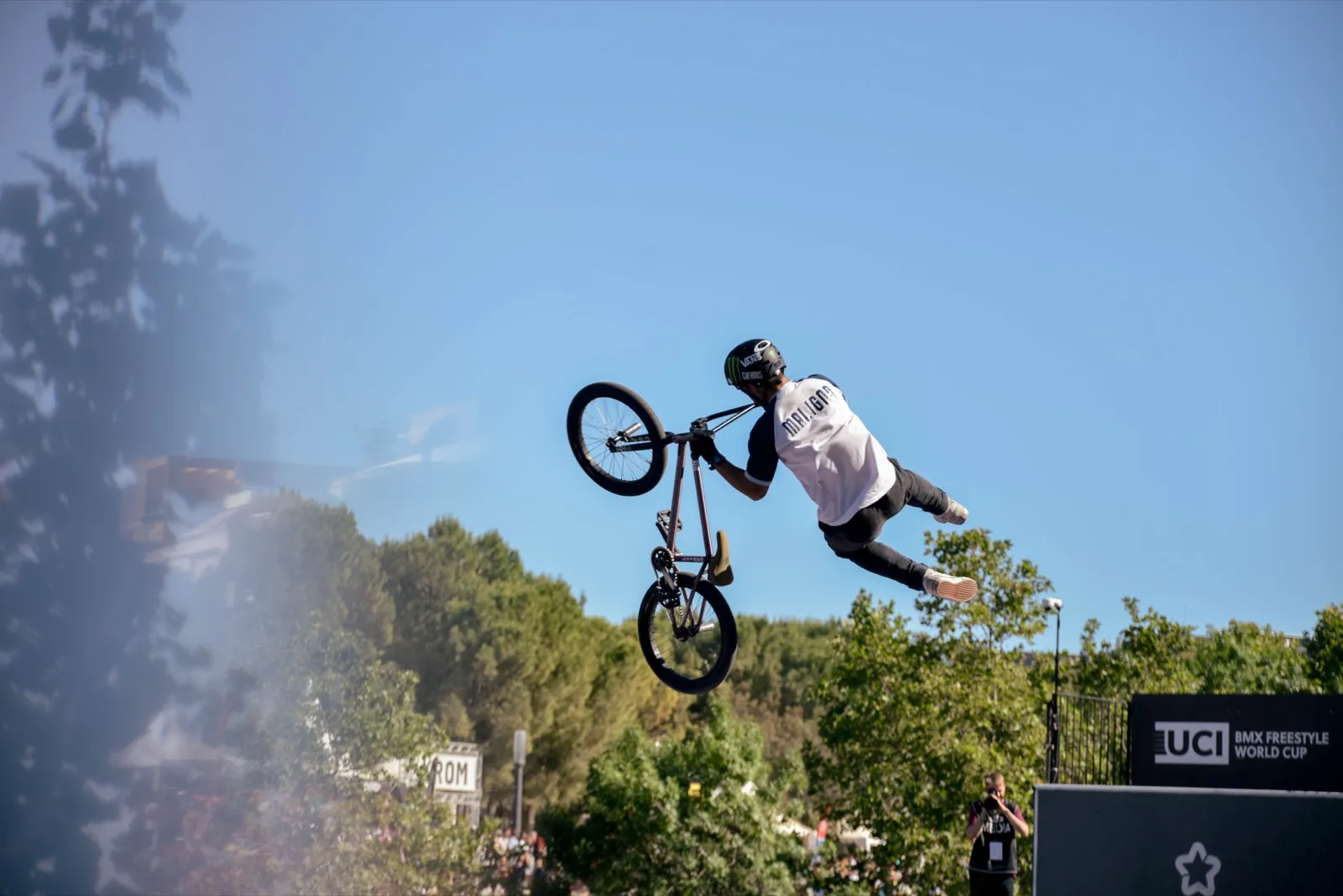 Figure aérienne en BMX, rider en pleine rotation sous un ciel dégagé.